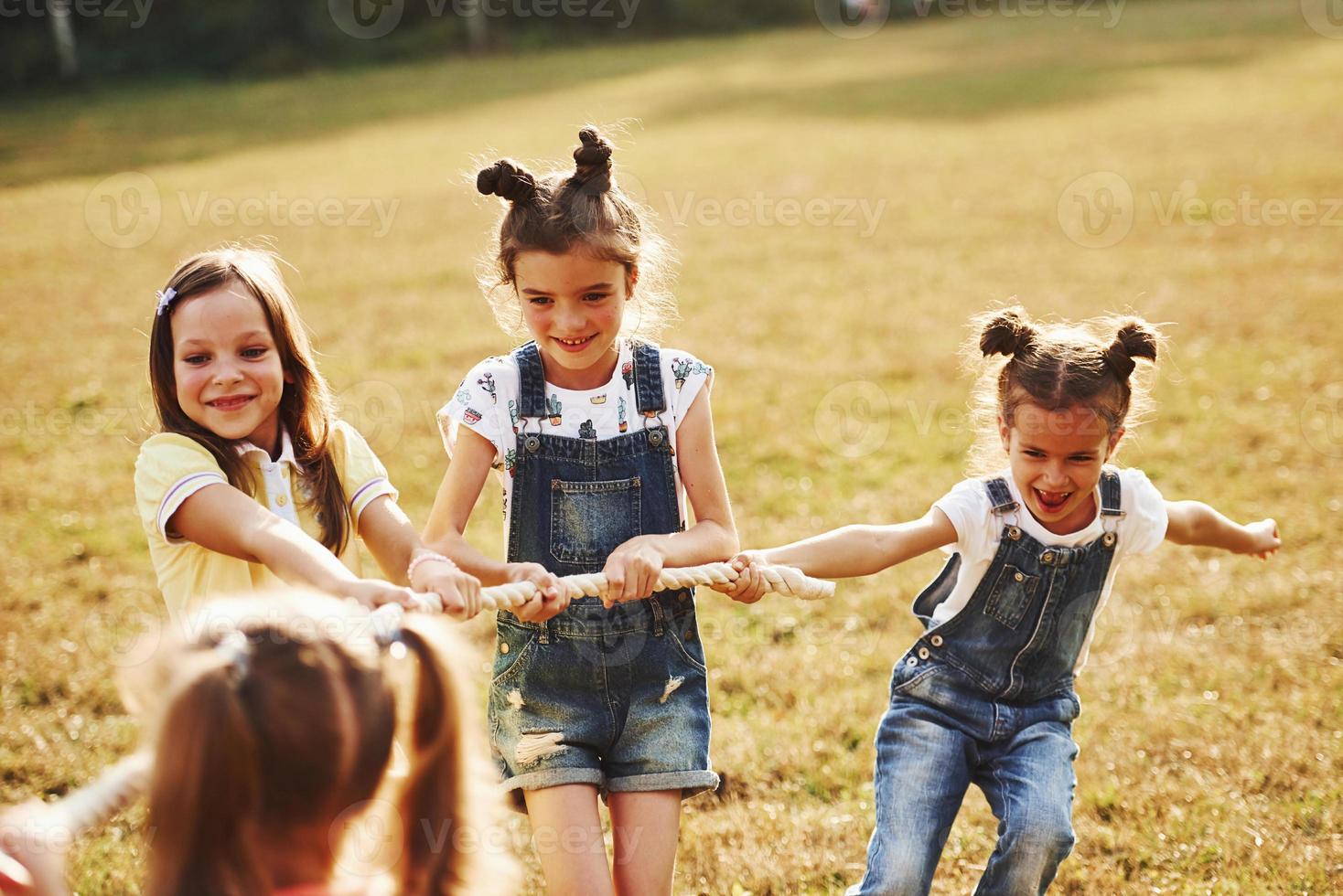 Kids playing tug of war game in the beautiful meadow at sunny day photo