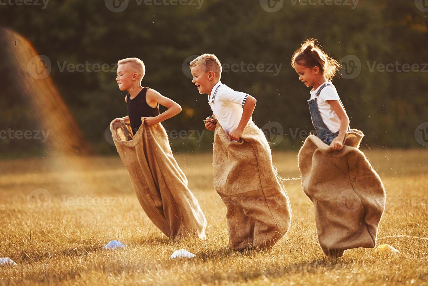 Jumping sack race outdoors in the field. Kids have fun at sunny daytime photo