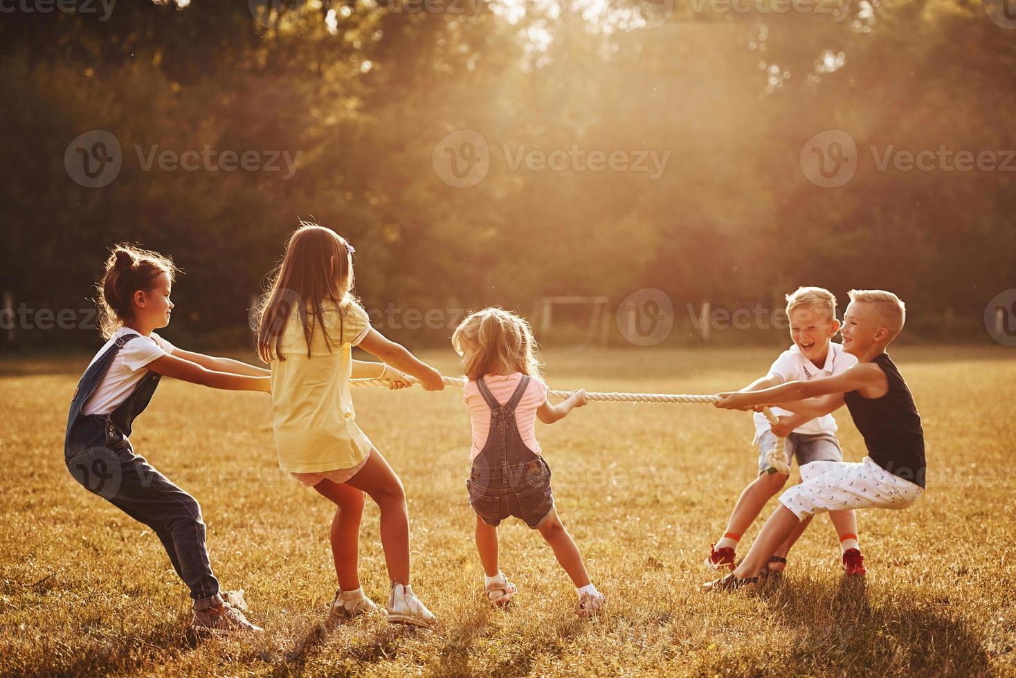 niños jugando tira y afloja en el hermoso prado en un día soleado foto