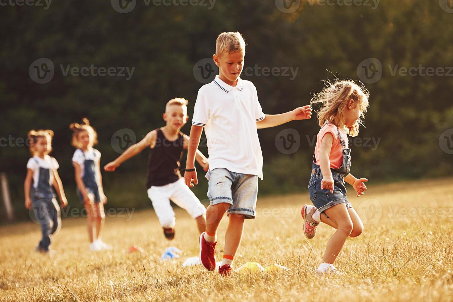 Through obstacles. Kids running in the field at sunny day. Conception of healthy lifestyle photo