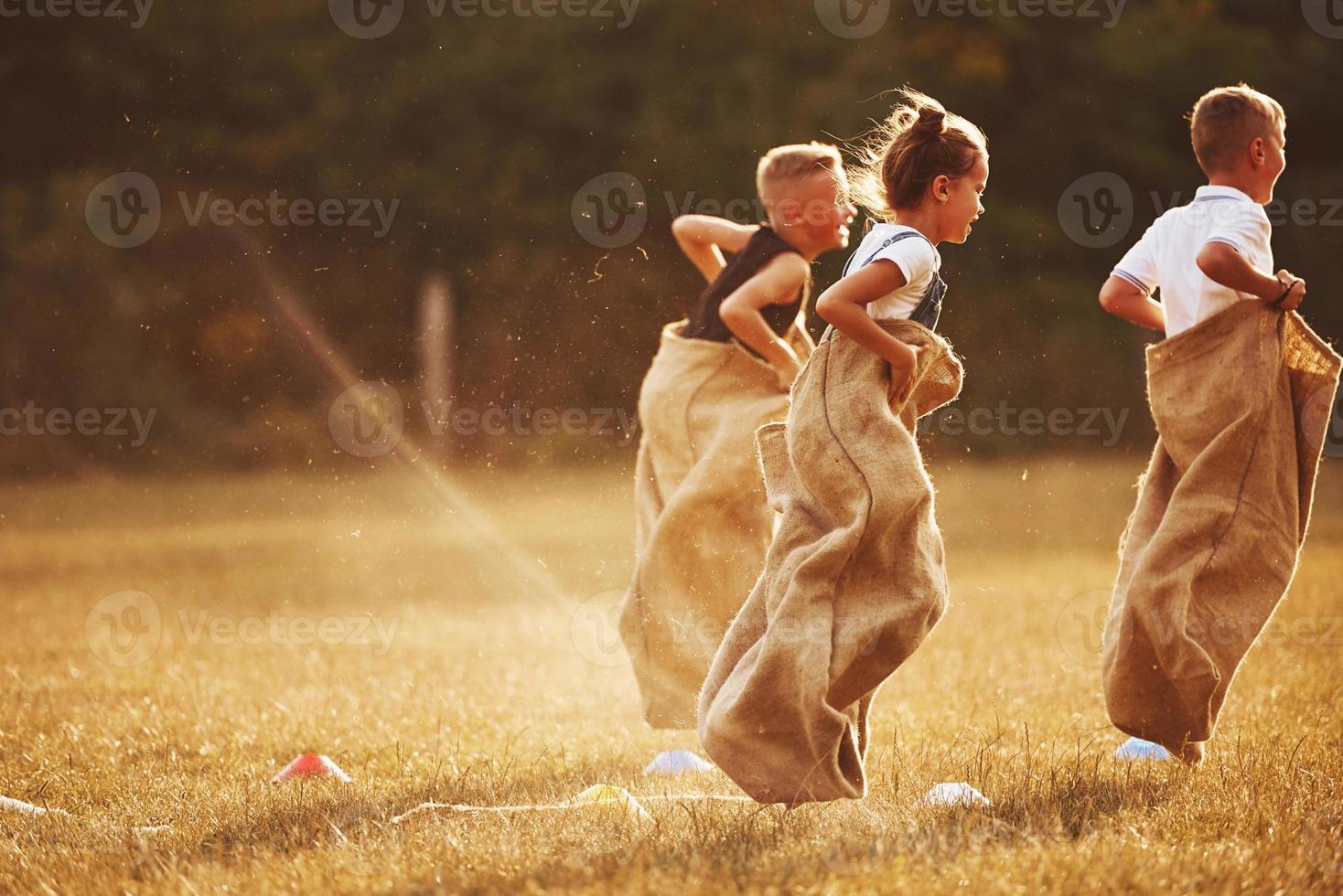 Jumping sack race outdoors in the field. Kids have fun at sunny daytime photo