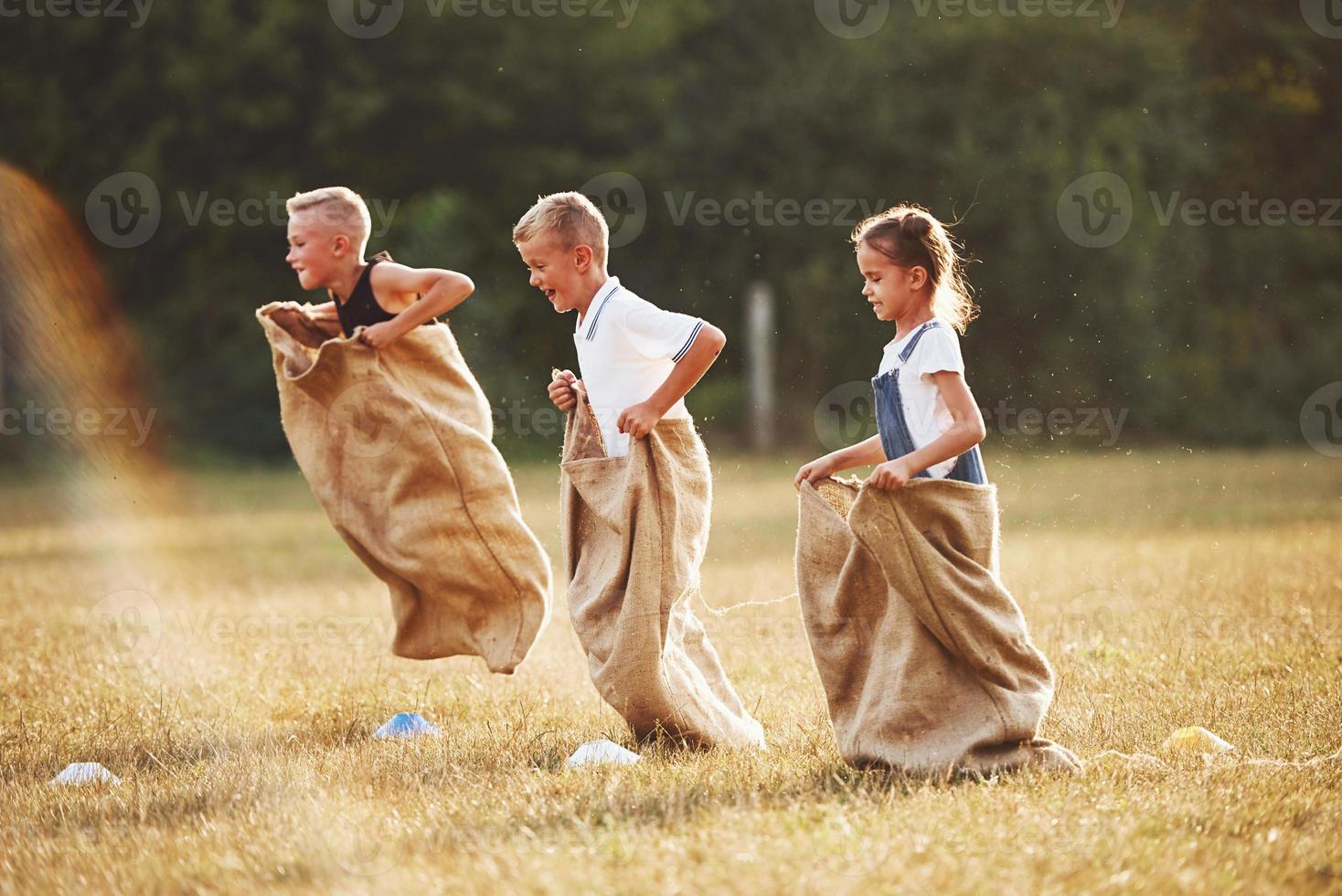 Jumping sack race outdoors in the field. Kids have fun at sunny daytime photo