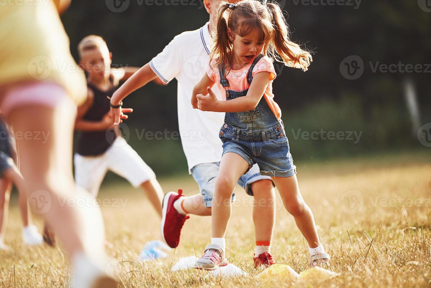 Through obstacles. Kids running in the field at sunny day. Conception of healthy lifestyle photo