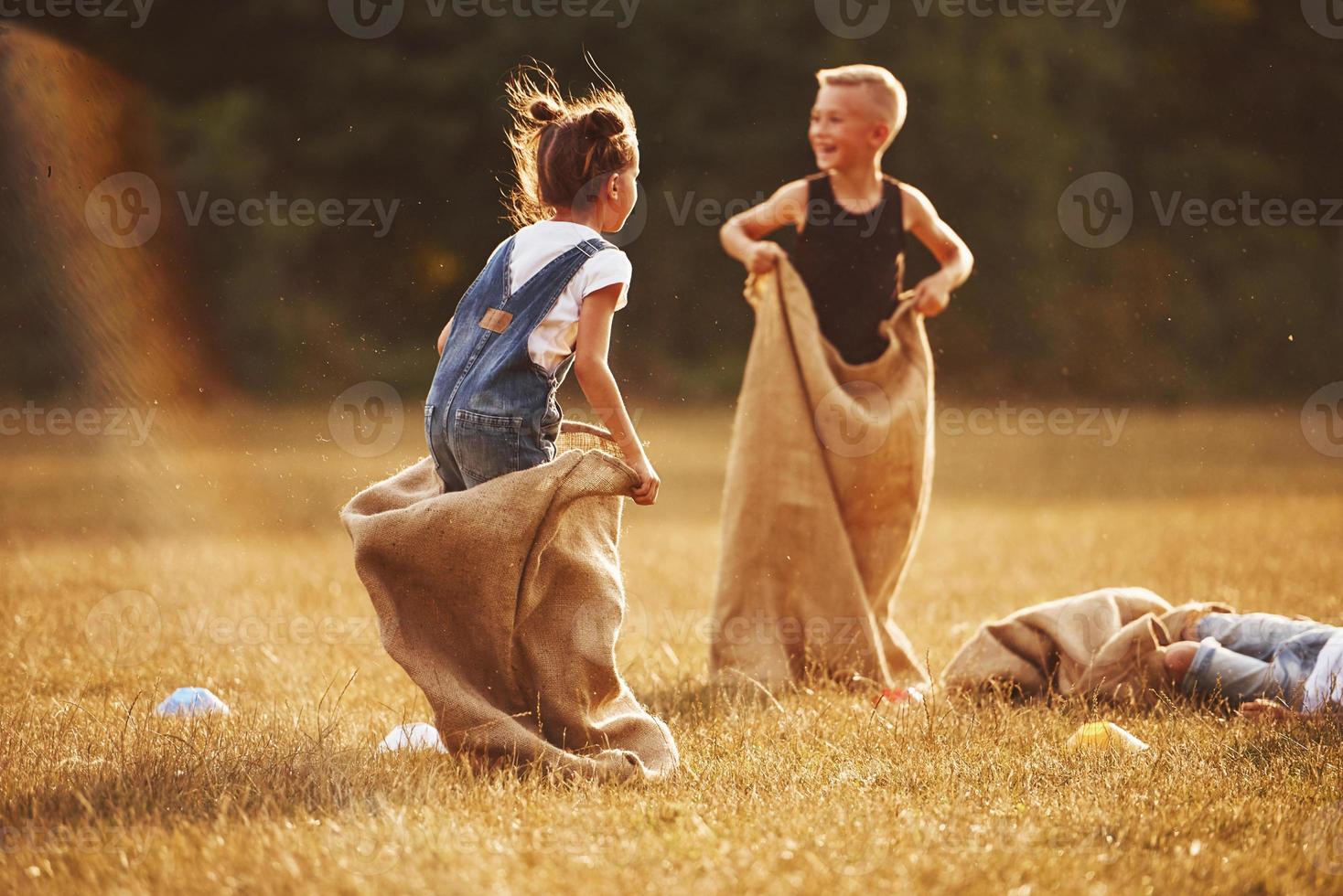 Jumping sack race outdoors in the field. Kids have fun at sunny daytime photo