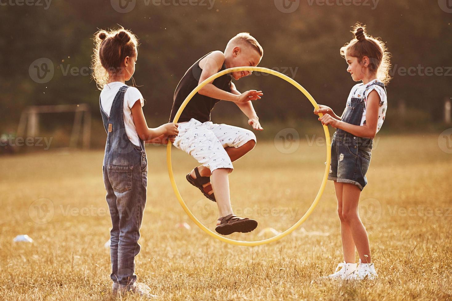 saltando a través de la herramienta de fitness circular. niños divirtiéndose en el campo foto