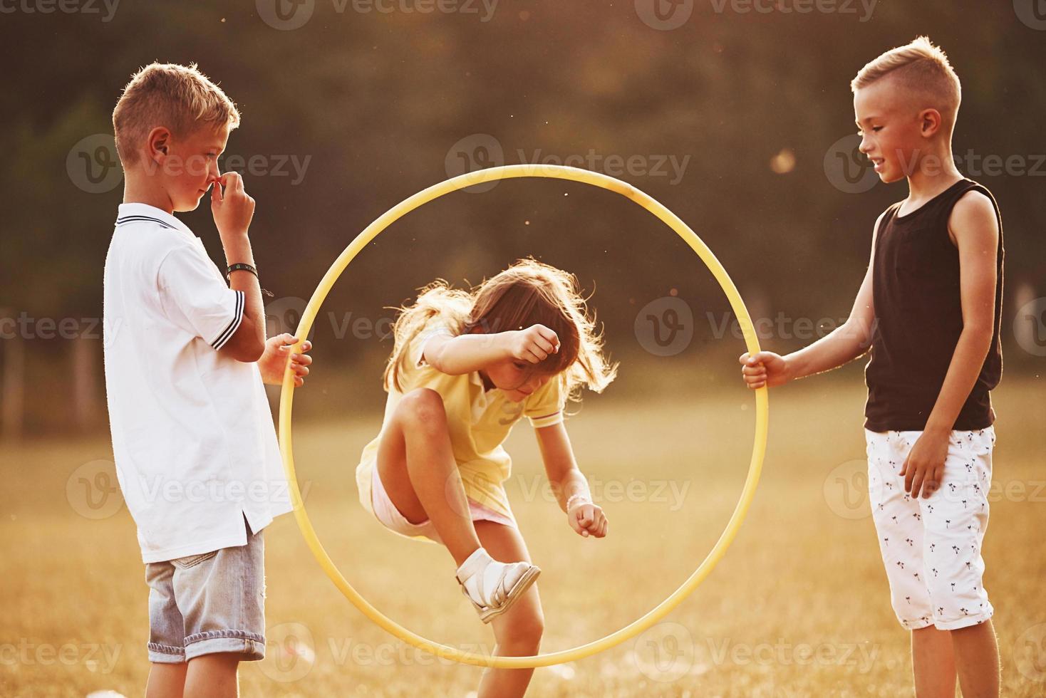 Jumping through the circle fitness tool. Kids having fun in the field photo