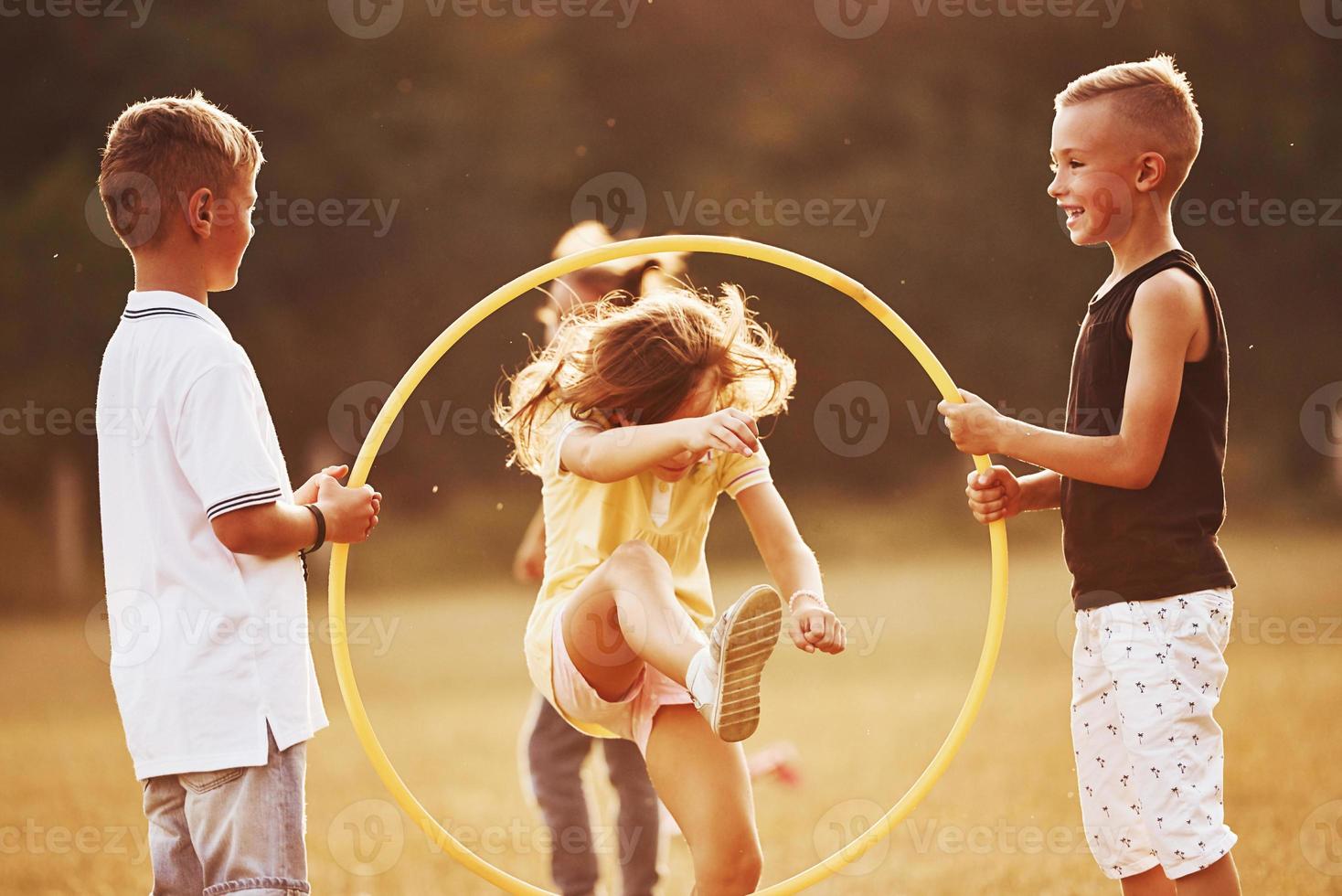 saltando a través de la herramienta de fitness circular. niños divirtiéndose en el campo foto