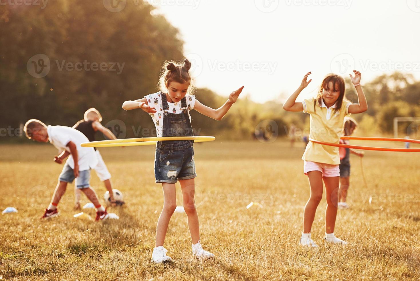 Girls with circle fitness tool. Group of kids have active weekend in the field photo