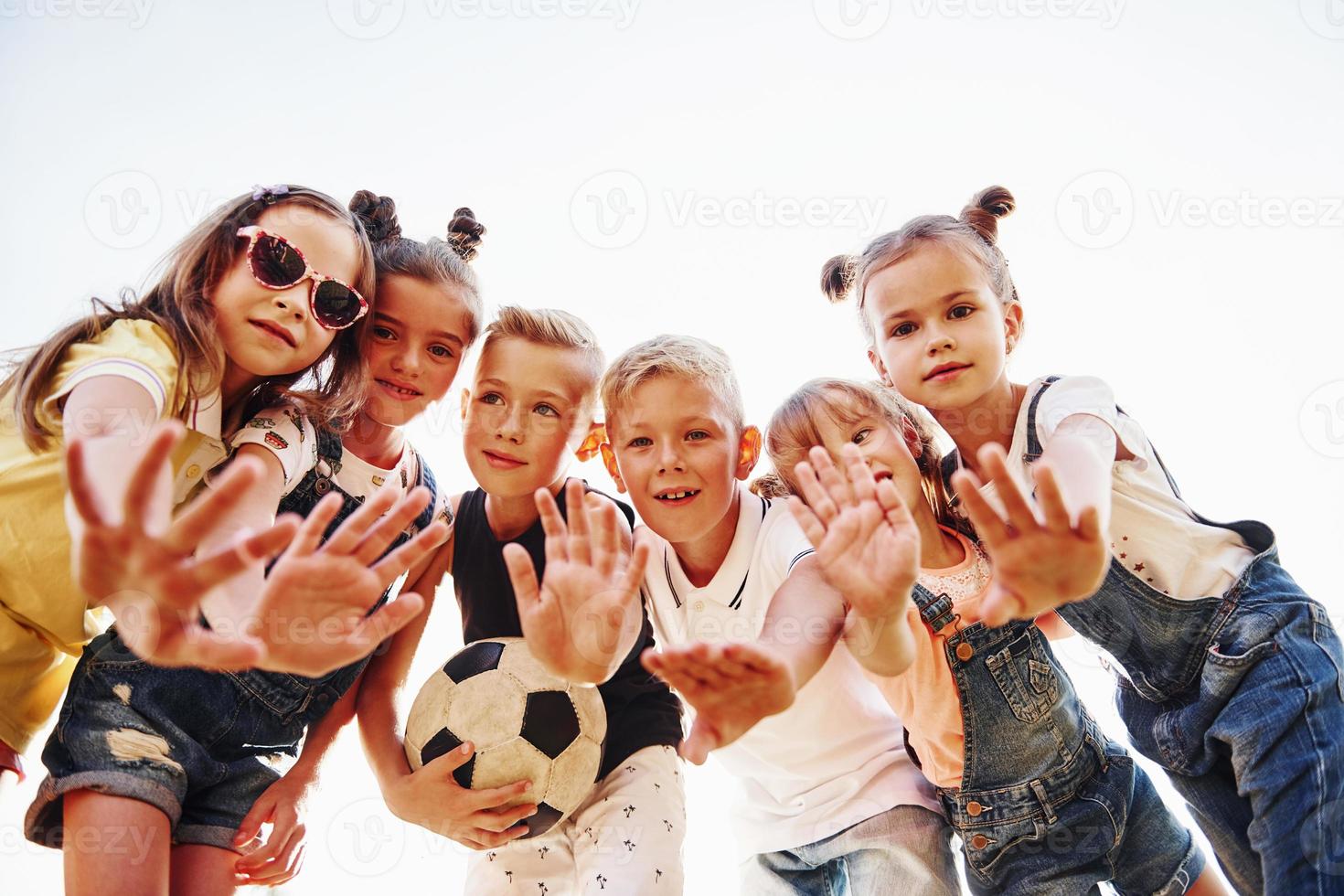 Hello, gesture. With soccer ball. Portrait of kids that standing together and posing for the camera photo