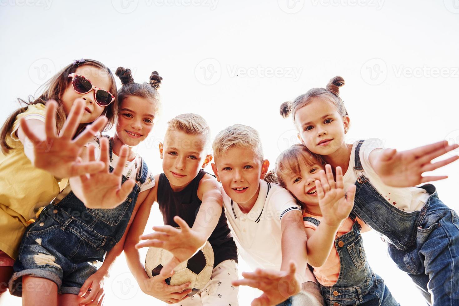 Hello, gesture. With soccer ball. Portrait of kids that standing together and posing for the camera photo