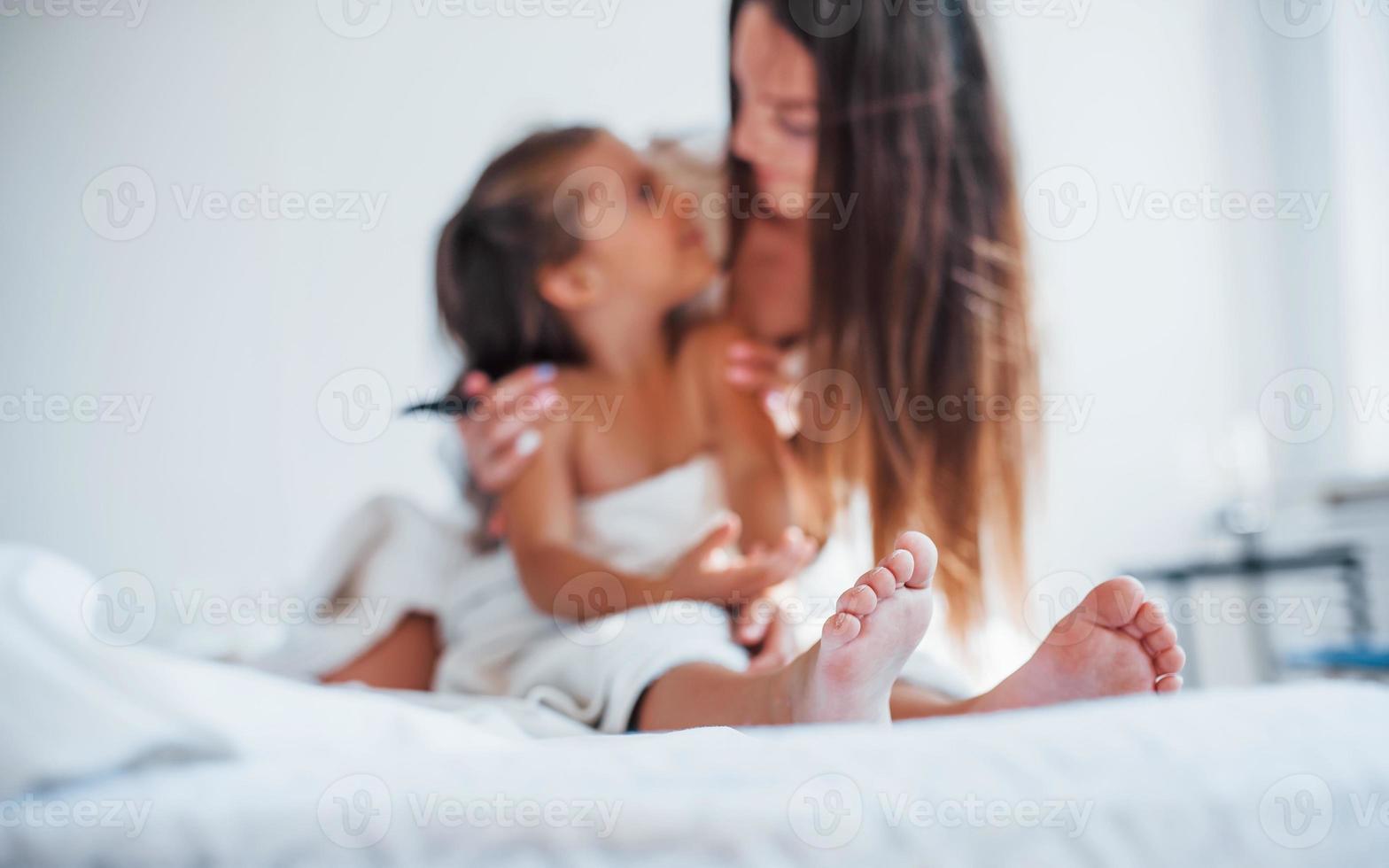 Focused photo. Young mother with her daugher have beauty day indoors in white room photo