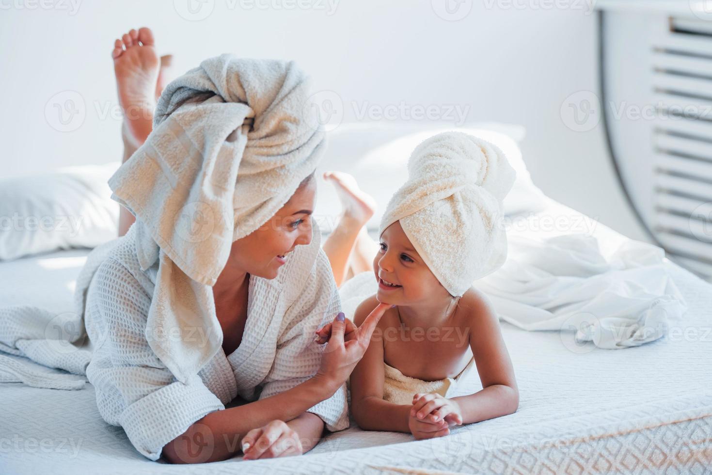 la joven madre con su hija tiene un día de belleza en el interior de la habitación blanca foto