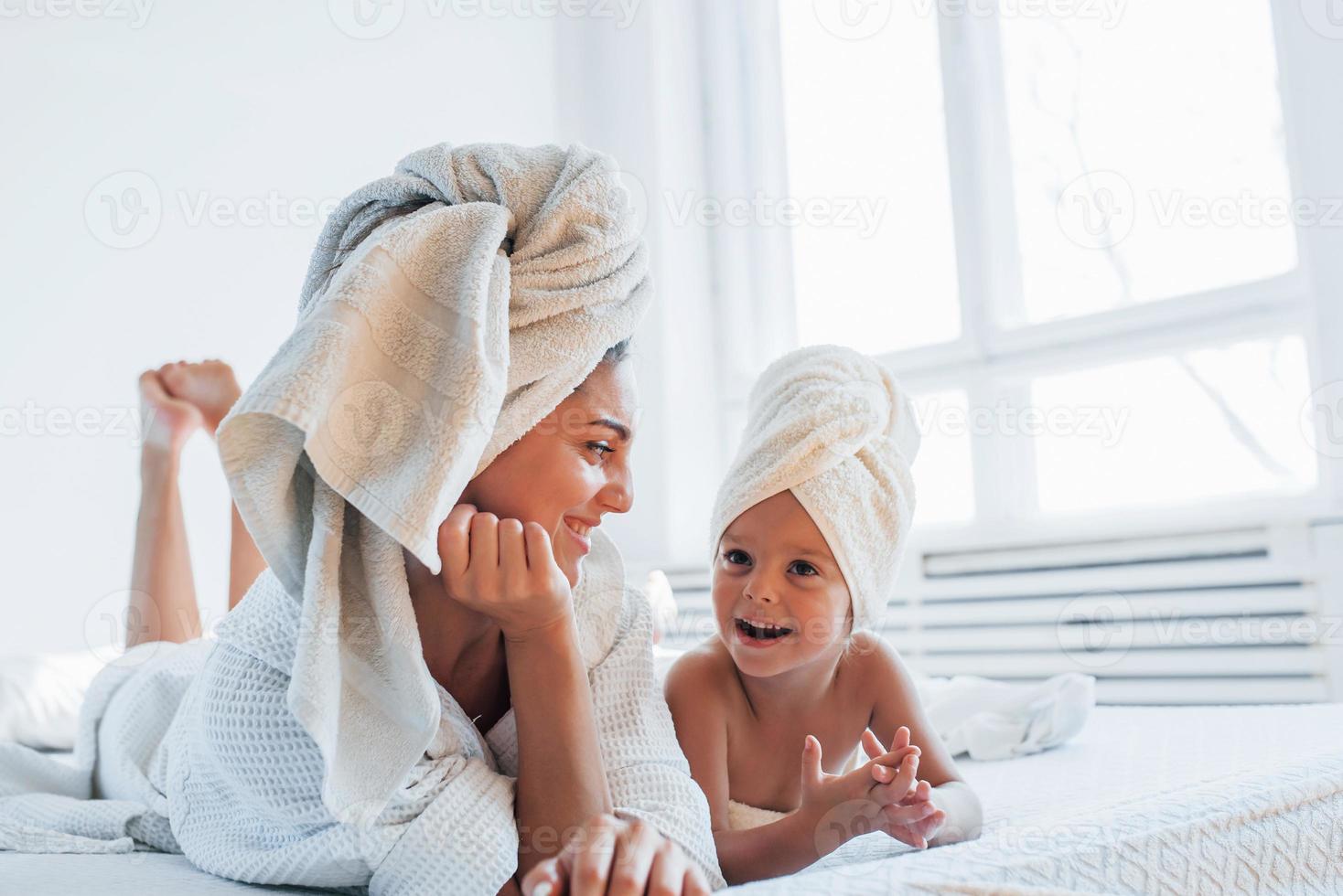 divirtiéndose. la joven madre con su hija tiene un día de belleza en el interior de la habitación blanca foto