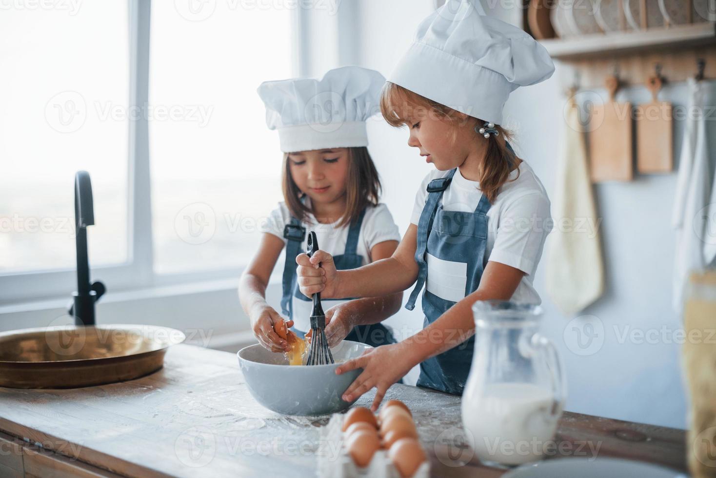 Family kids in white chef uniform preparing food on the kitchen photo