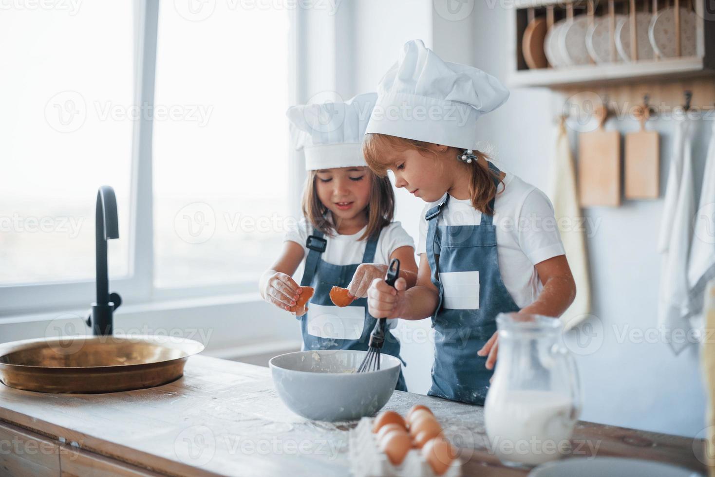 niños de familia con uniforme de chef blanco preparando comida en la cocina foto