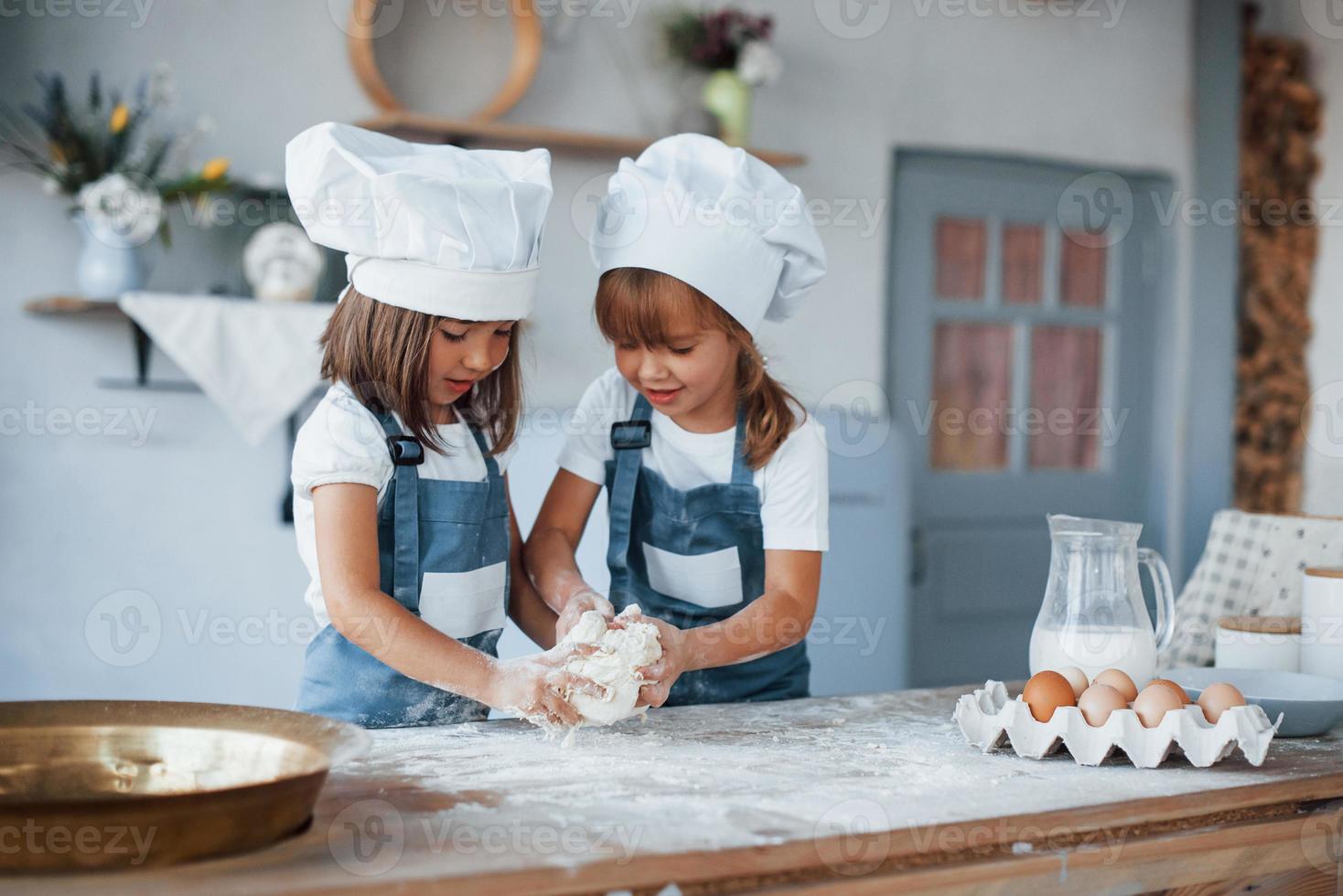 niños de familia con uniforme de chef blanco preparando comida en la cocina foto