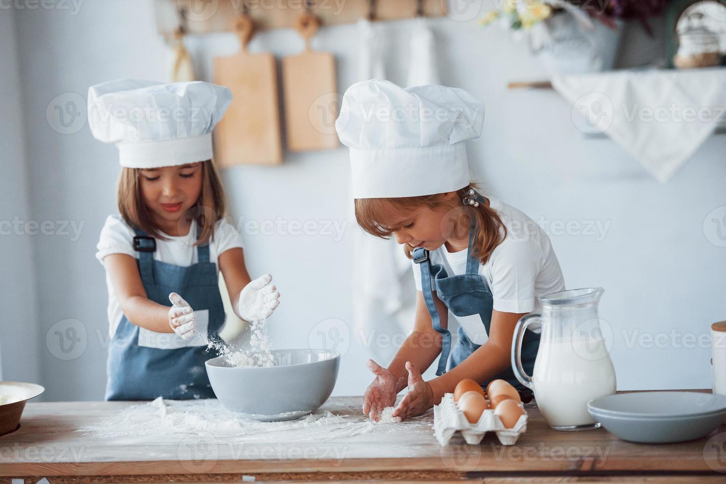 Family kids in white chef uniform preparing food on the kitchen photo