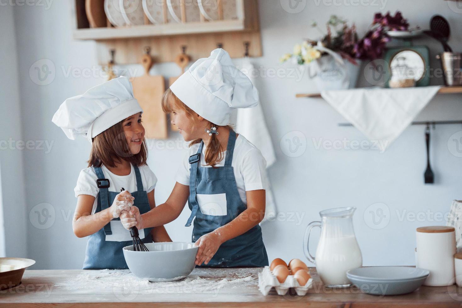 niños de familia con uniforme de chef blanco preparando comida en la cocina foto