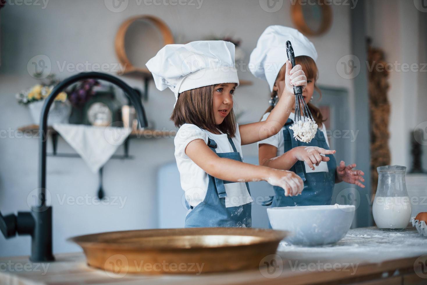 niños de familia con uniforme de chef blanco preparando comida en la cocina foto