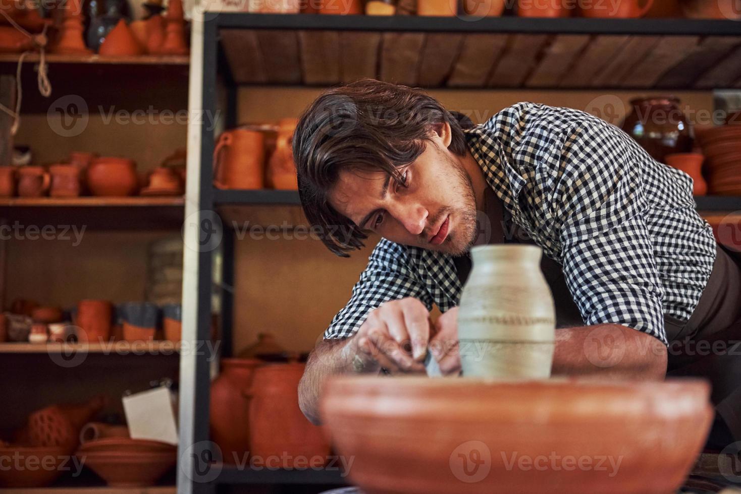 Detailing by special tool. Ceramist uses potter's wheel and creates a handmade clay product photo