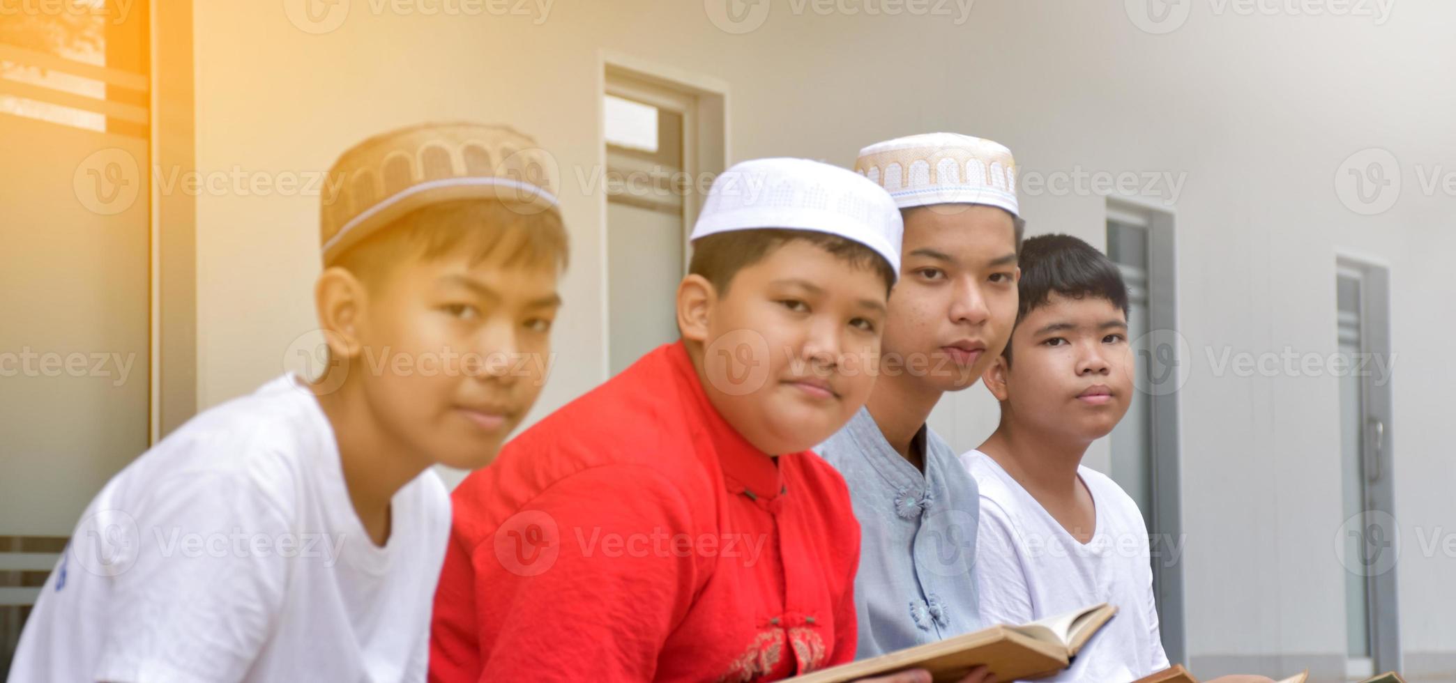 Asian muslim or islamic boys sitting with muslim boys in a row to pray or to do the religious activity, soft and selective focus. photo