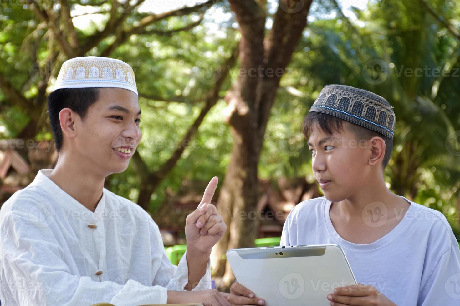 Asian muslim boys sit together in school park to read and learn their daily activity and do homework in their free times before going back home, soft and selective focus. photo