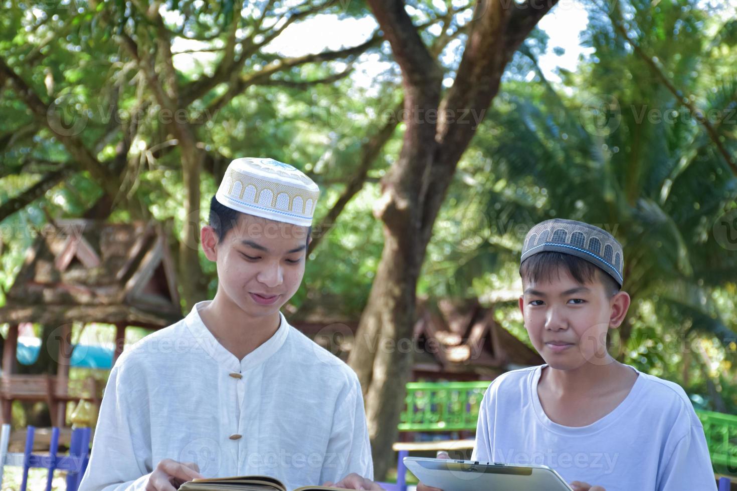 Asian muslim boys sit together in school park to read and learn their daily activity and do homework in their free times before going back home, soft and selective focus. photo