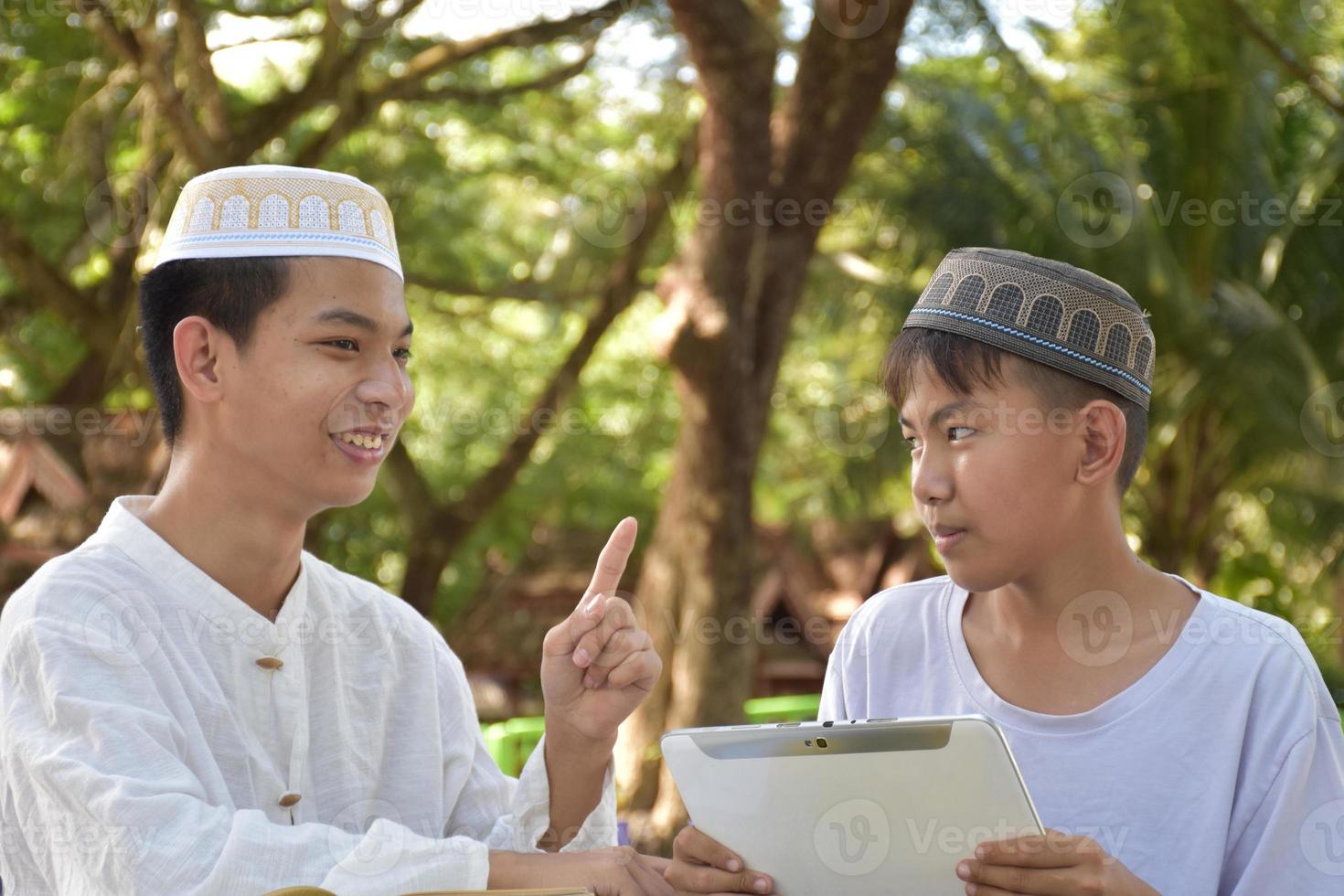 Asian muslim boys sit together in school park to read and learn their daily activity and do homework in their free times before going back home, soft and selective focus. photo