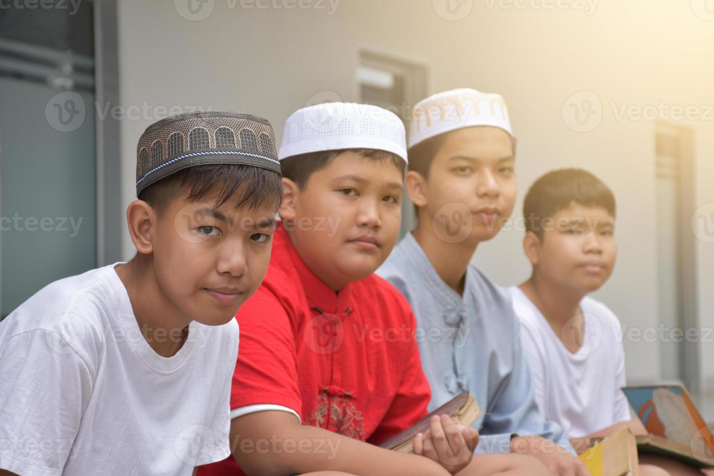 Asian muslim or islamic boys sitting with muslim boys in a row to pray or to do the religious activity, soft and selective focus. photo
