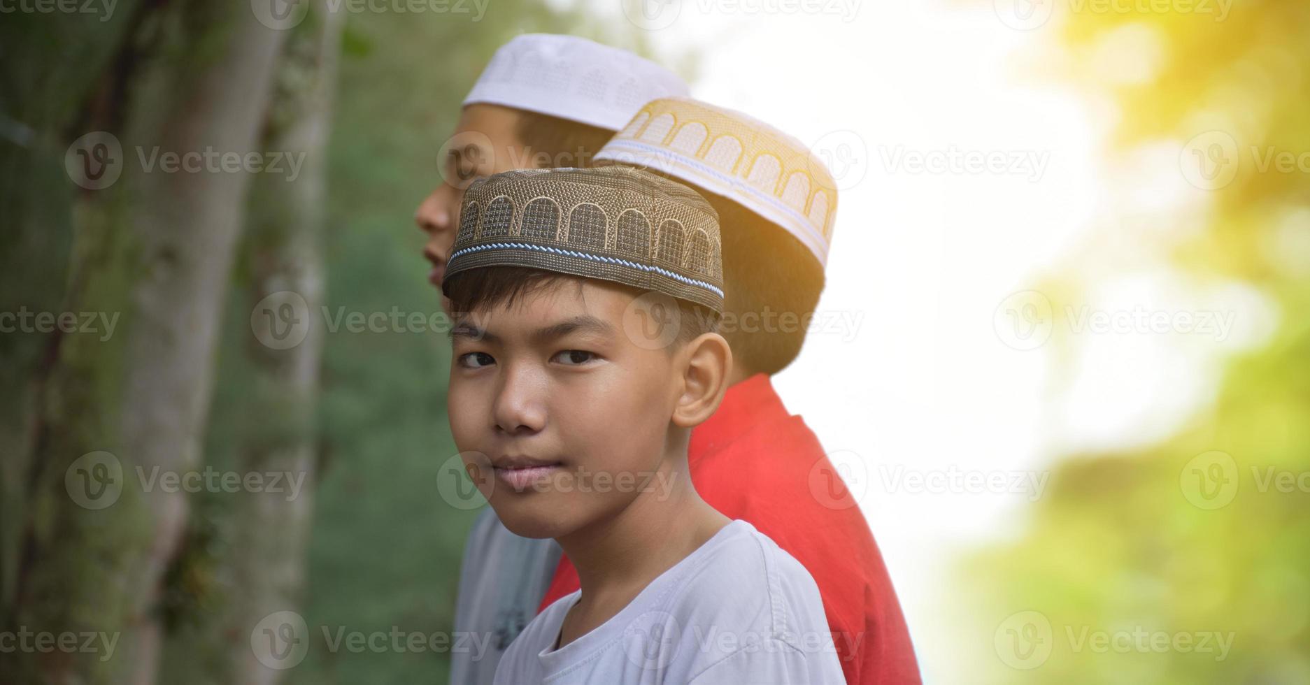 retrato de niños musulmanes o islámicos asiáticos parados juntos frente al árbol y esperando para hacer la actividad religiosa en la escuela, enfoque suave y selectivo. foto