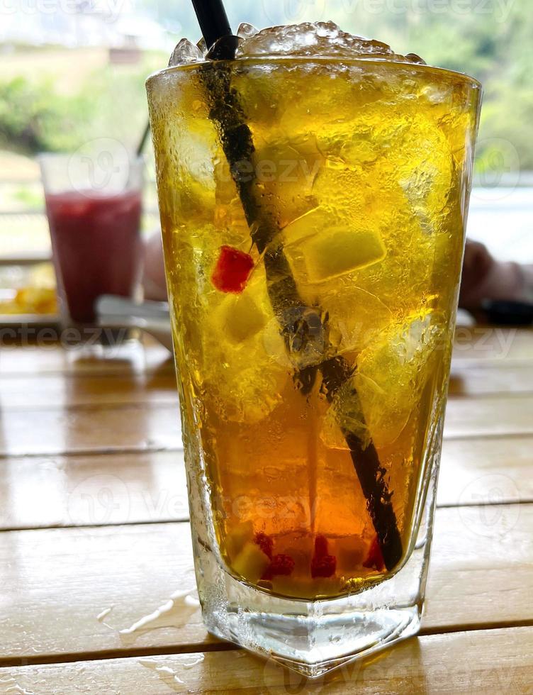 fresh mix fruit cocktail alcohol drink with rum and whiskey in a clear glass and chunk of ice photo