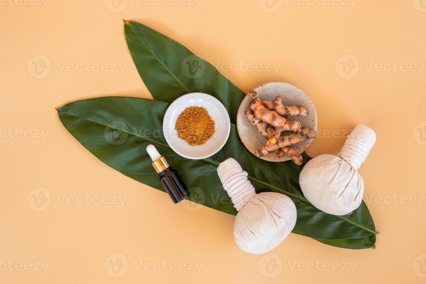 Top view of herbal compress ball with Thai herbal, turmeric, essential oil and bar soap on orange pastel background. Spa background concept. photo
