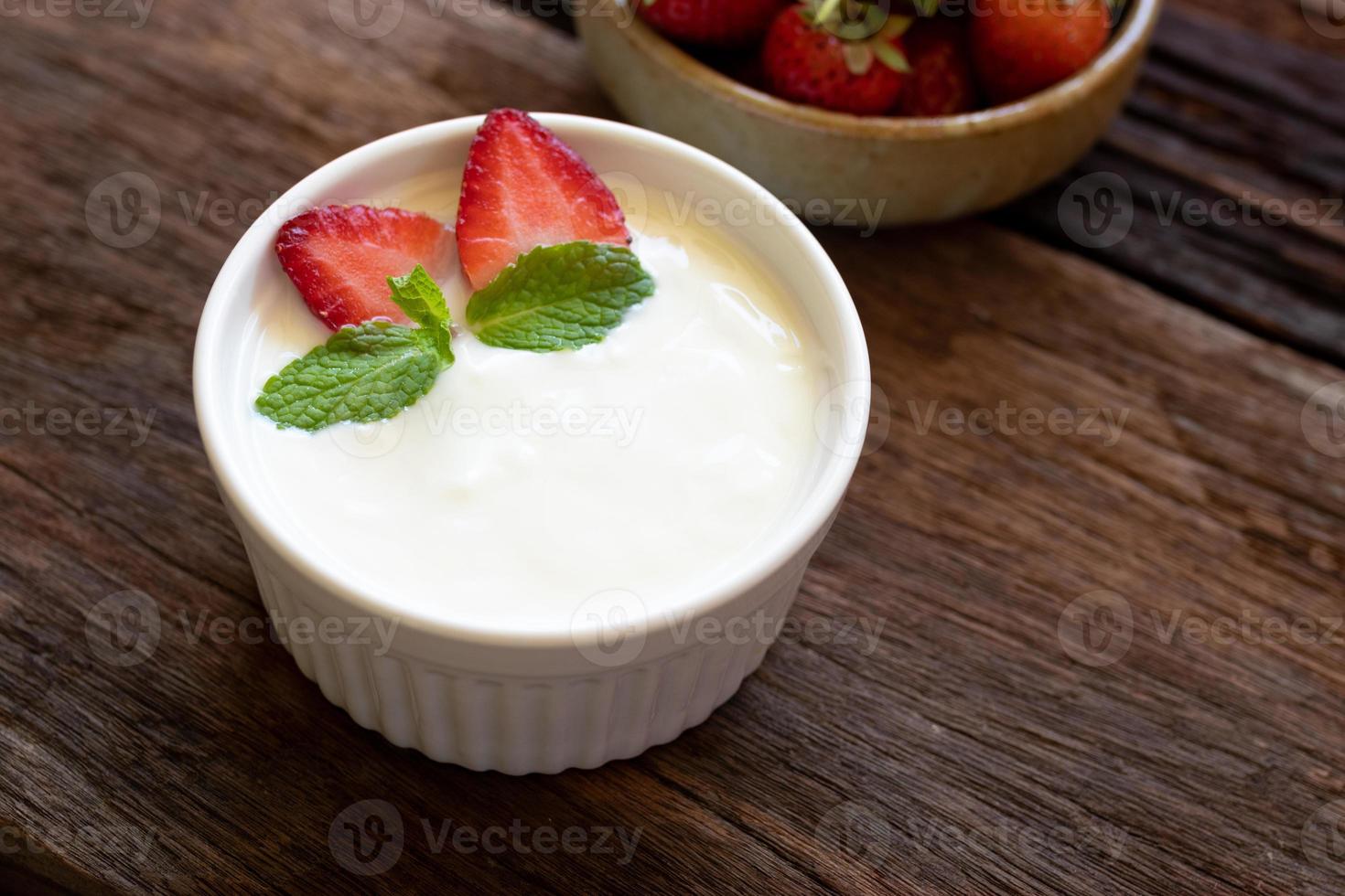 Strawberry yogurt in a wooden bowl with mint and fresh strawberry on wooden background. Health food concept. photo