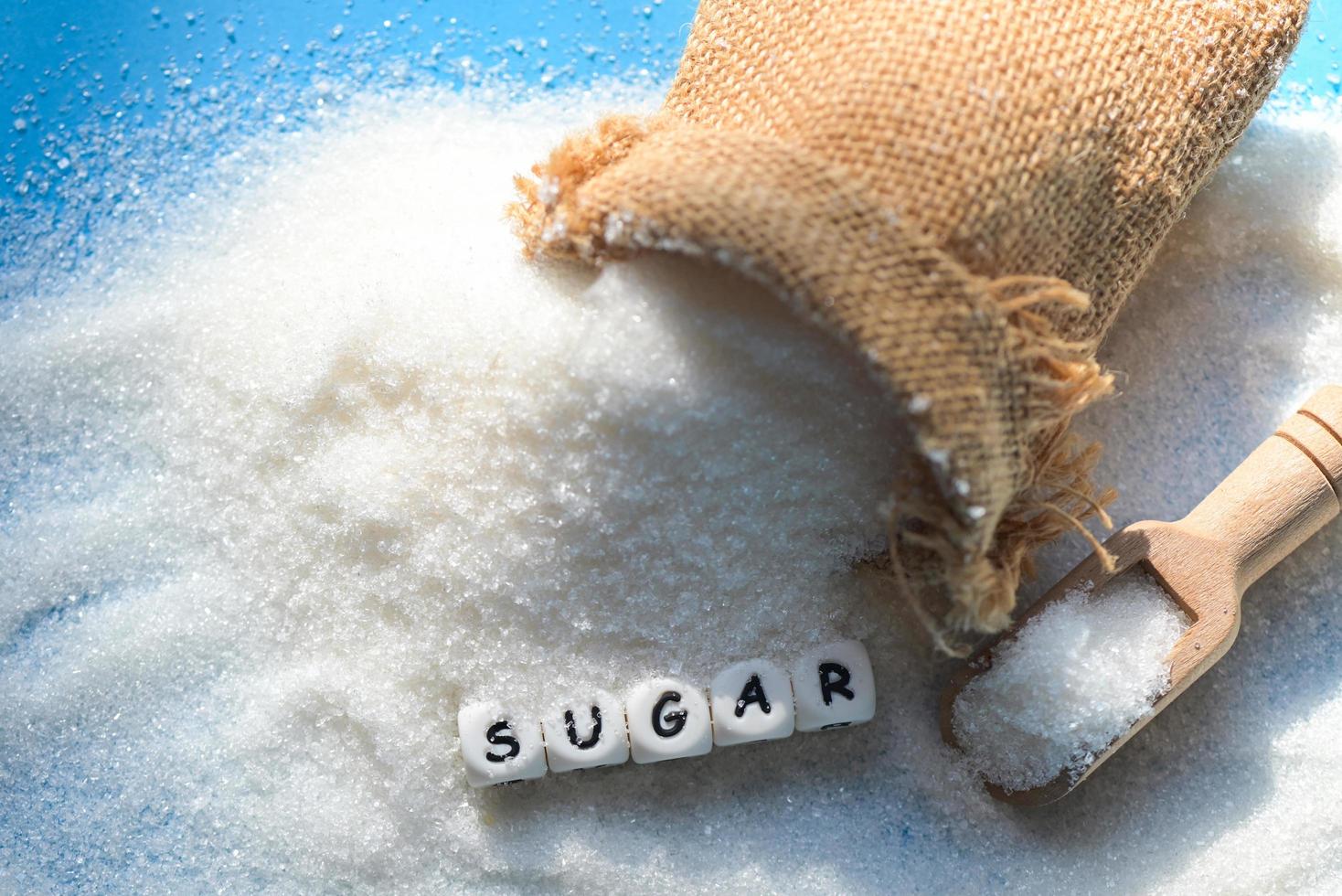 Sugar on sack and blue background, white sugar for food and sweets dessert candy heap of sweet sugar crystalline granulated photo