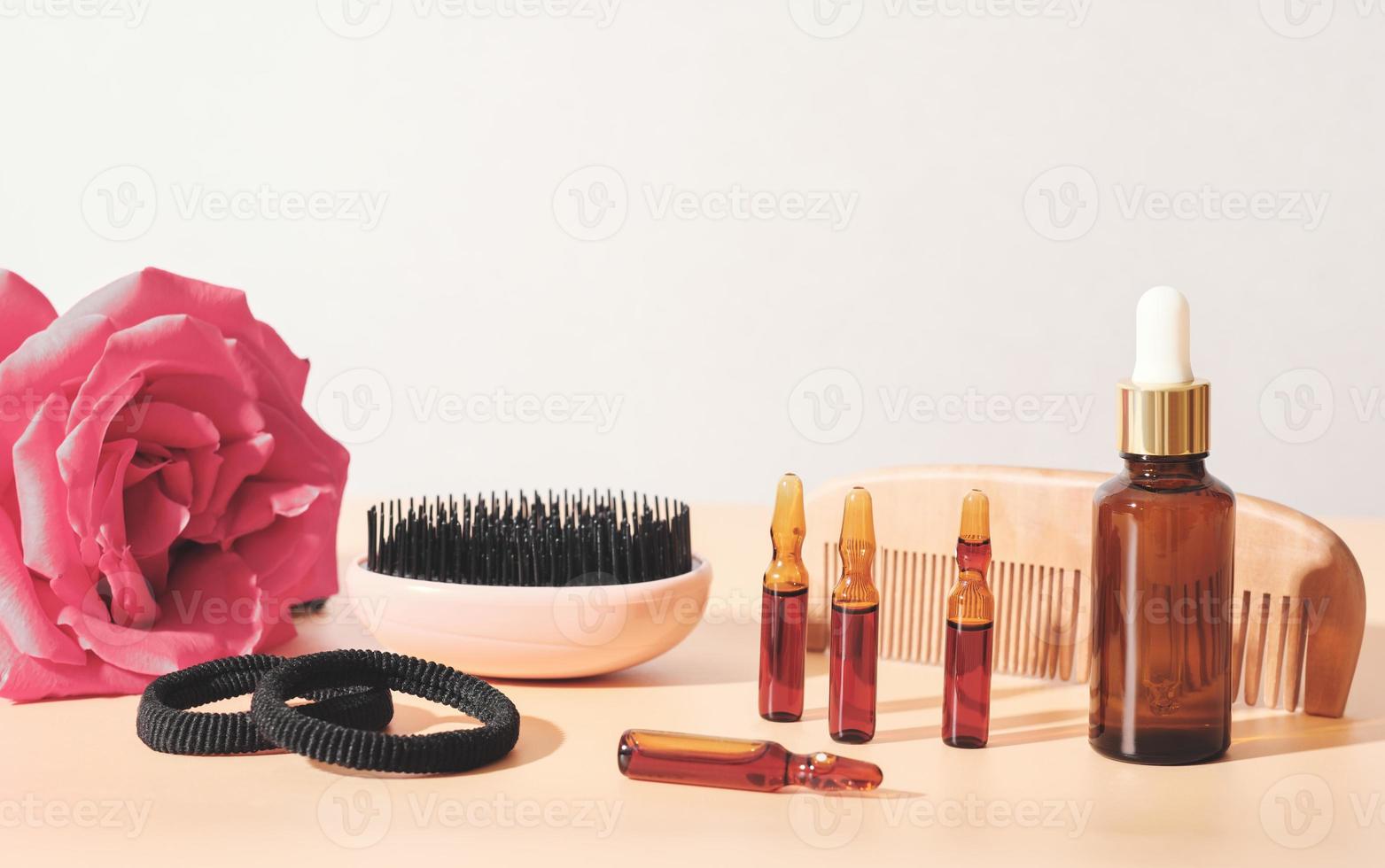 hair care solution in a dropper bottle and ampules, comb brush and hair ties. scalp treatment for weak and damaged hair. photo