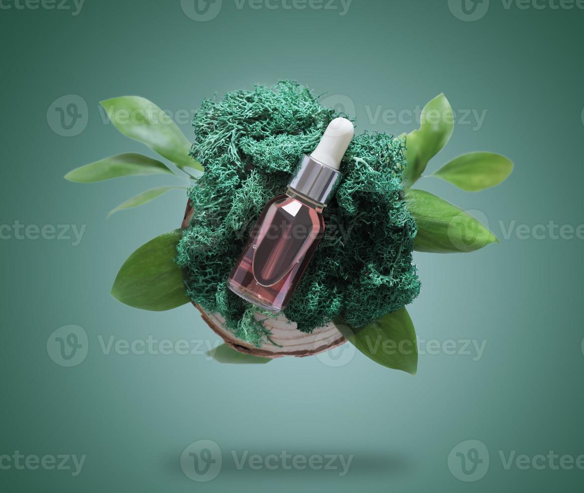 a dropper bottle of face serum or skin care oil on natural moss and green leaves. creative levitation set on green background. Flying bottle of face nourishing solution. photo