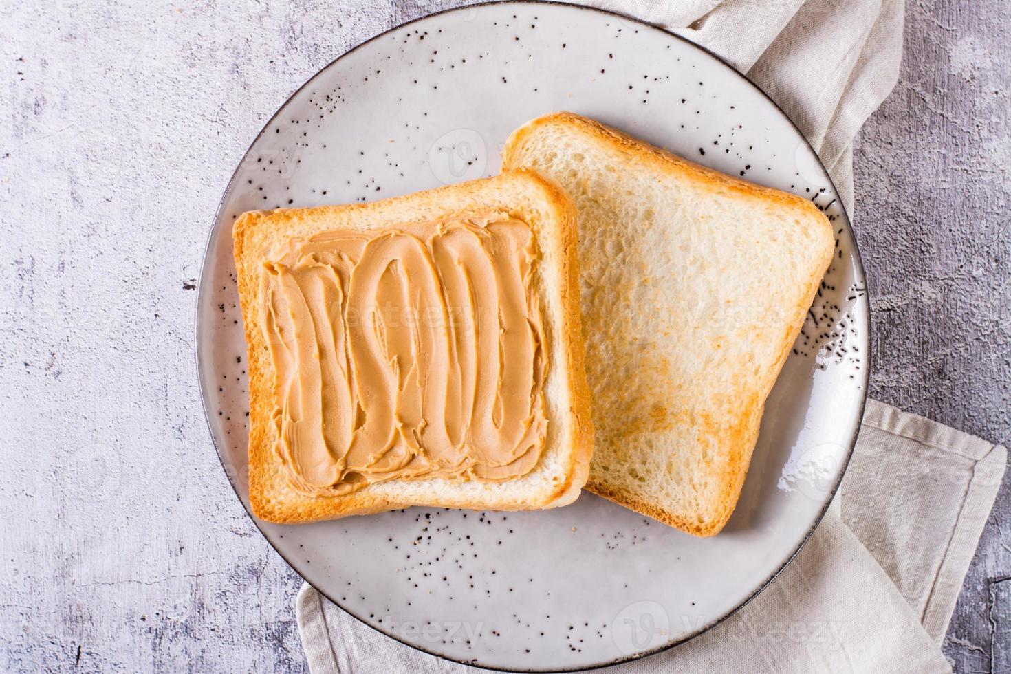 Peanut butter sandwich on toasted bread on a plate on the table. Top view. Closeup photo