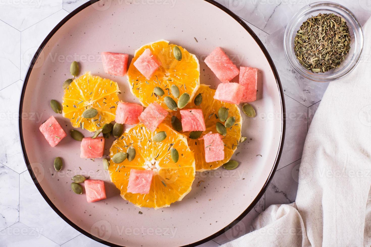 Fruit salad of watermelon, orange and pumpkin seeds on a plate. Healthy food. Top view. Closeup photo