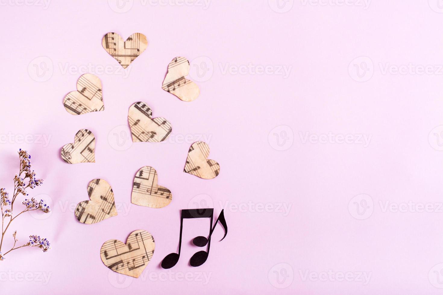 Paper hearts, notes and dry flowers on a pink background. Love music concept. Top view. photo