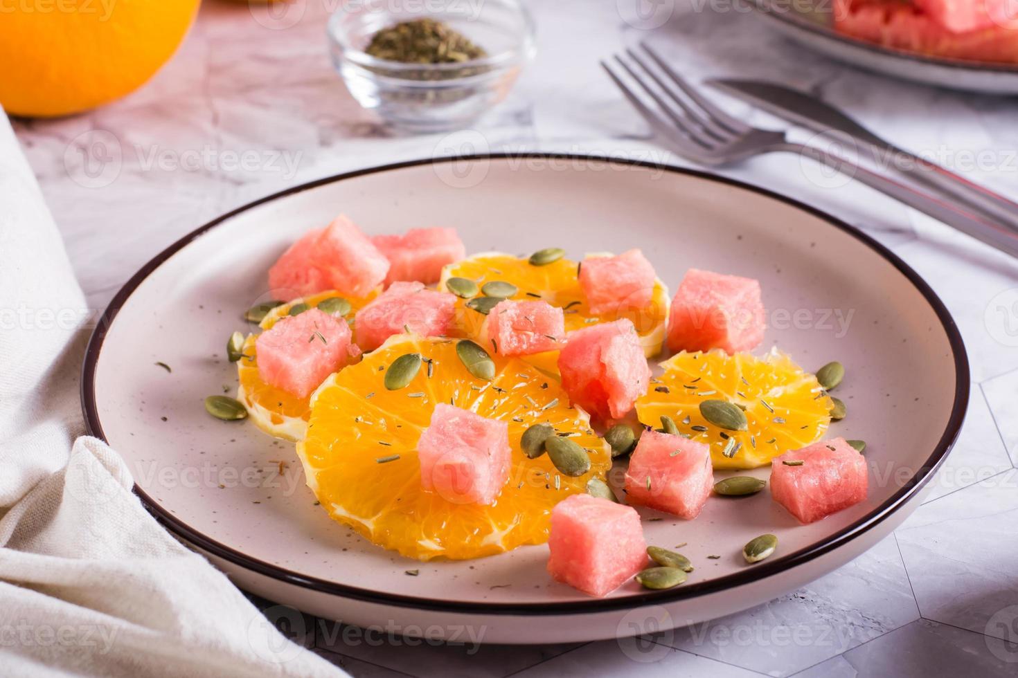 ensalada de frutas de sandía, naranja y semillas de calabaza en un plato sobre la mesa. comida sana. foto