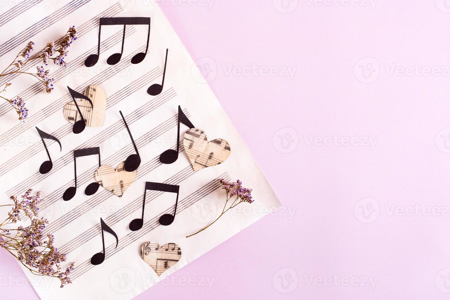 The concept of love for music. Paper notes and hearts on a music sheet. Top view photo