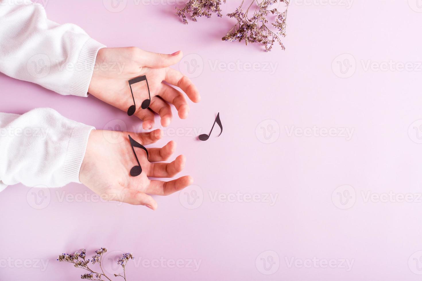 Children's hands hold paper notes on a pink background. Music education. Top view. photo