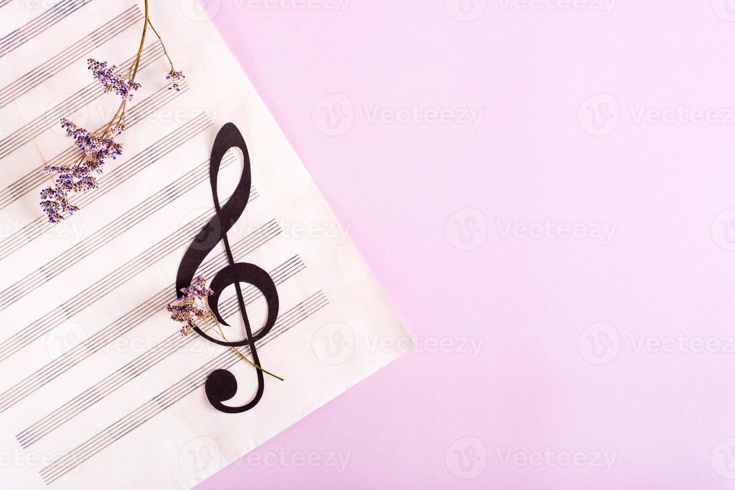 Paper musical clef on a sheet of music and dried flowers. Top view. photo