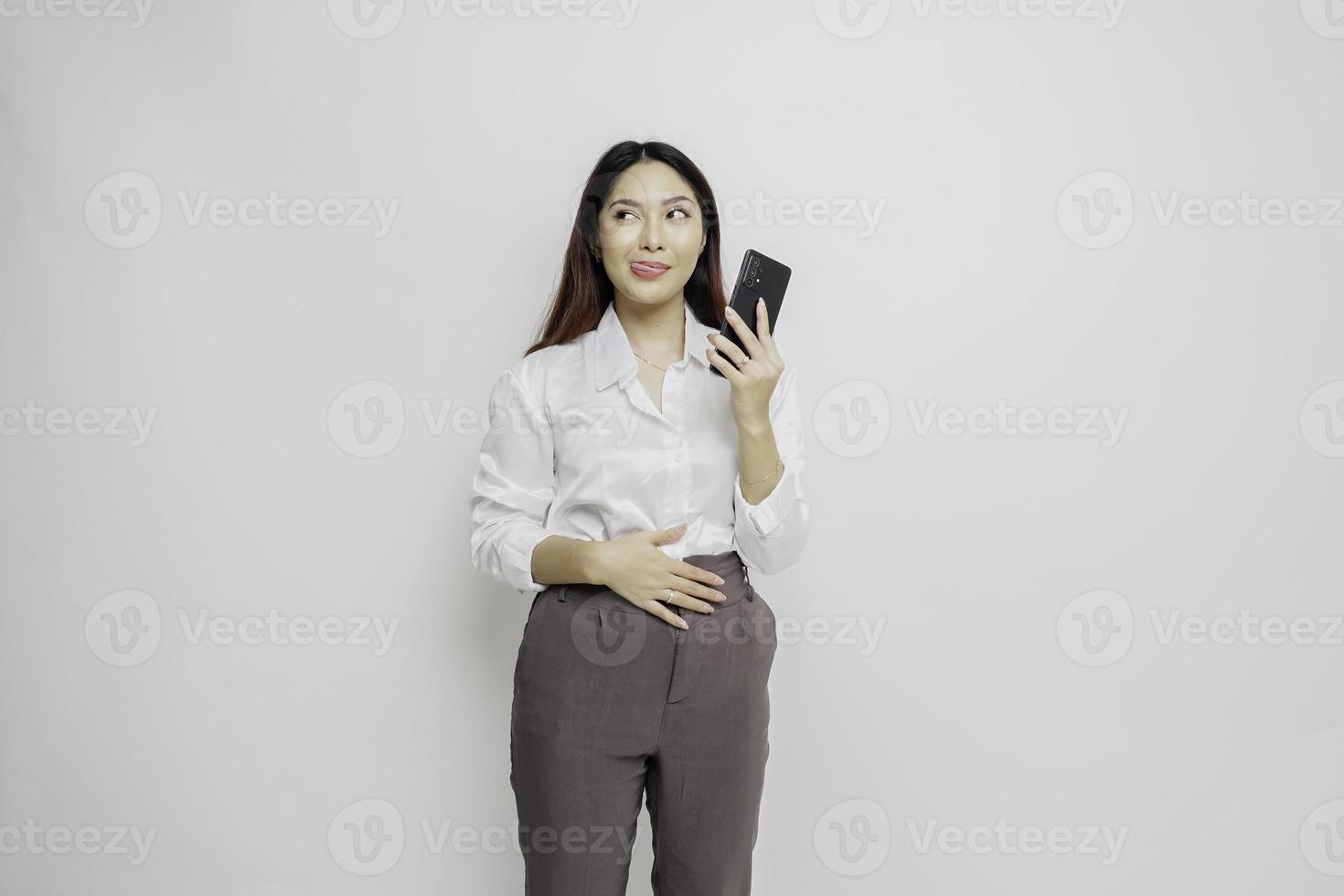 Photo of a hungry excited young woman holding her phone and wondering what to order yummy food isolated on white color background