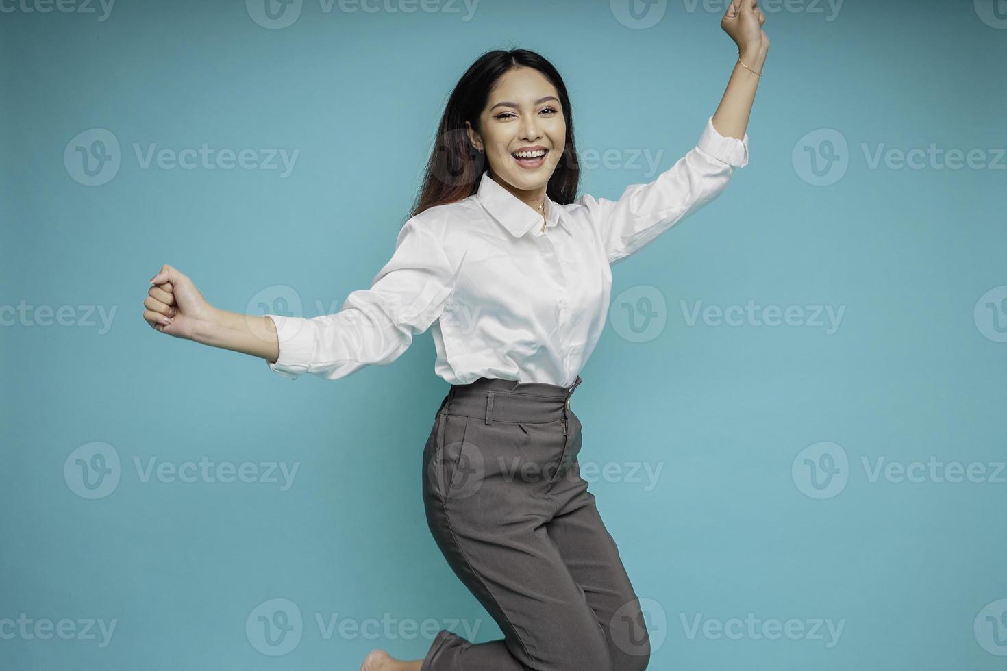 Photo of active Asian girl or employee jump raise hands up wear white shirt isolated blue color background
