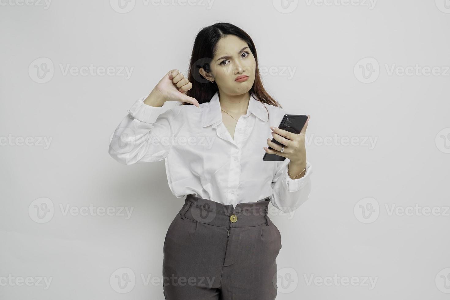 Disappointed Asian businesswoman gives thumbs down hand gesture of