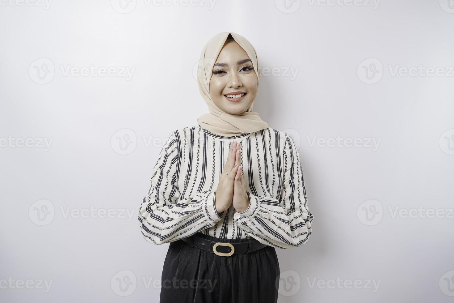 Portrait of a young beautiful Muslim woman wearing a hijab gesturing Eid Mubarak greeting photo