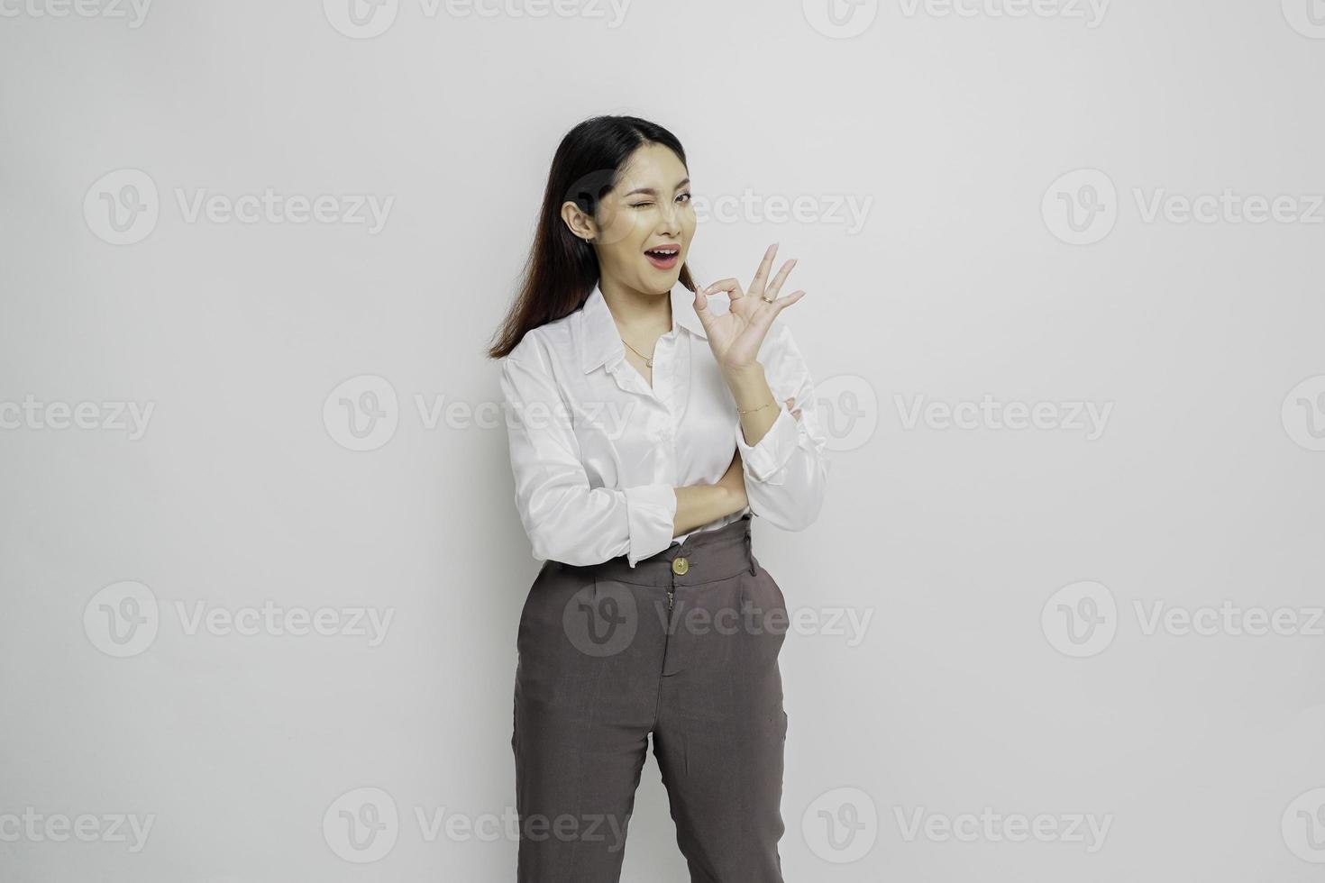 Excited Asian woman giving an OK hand gesture isolated by a white background photo