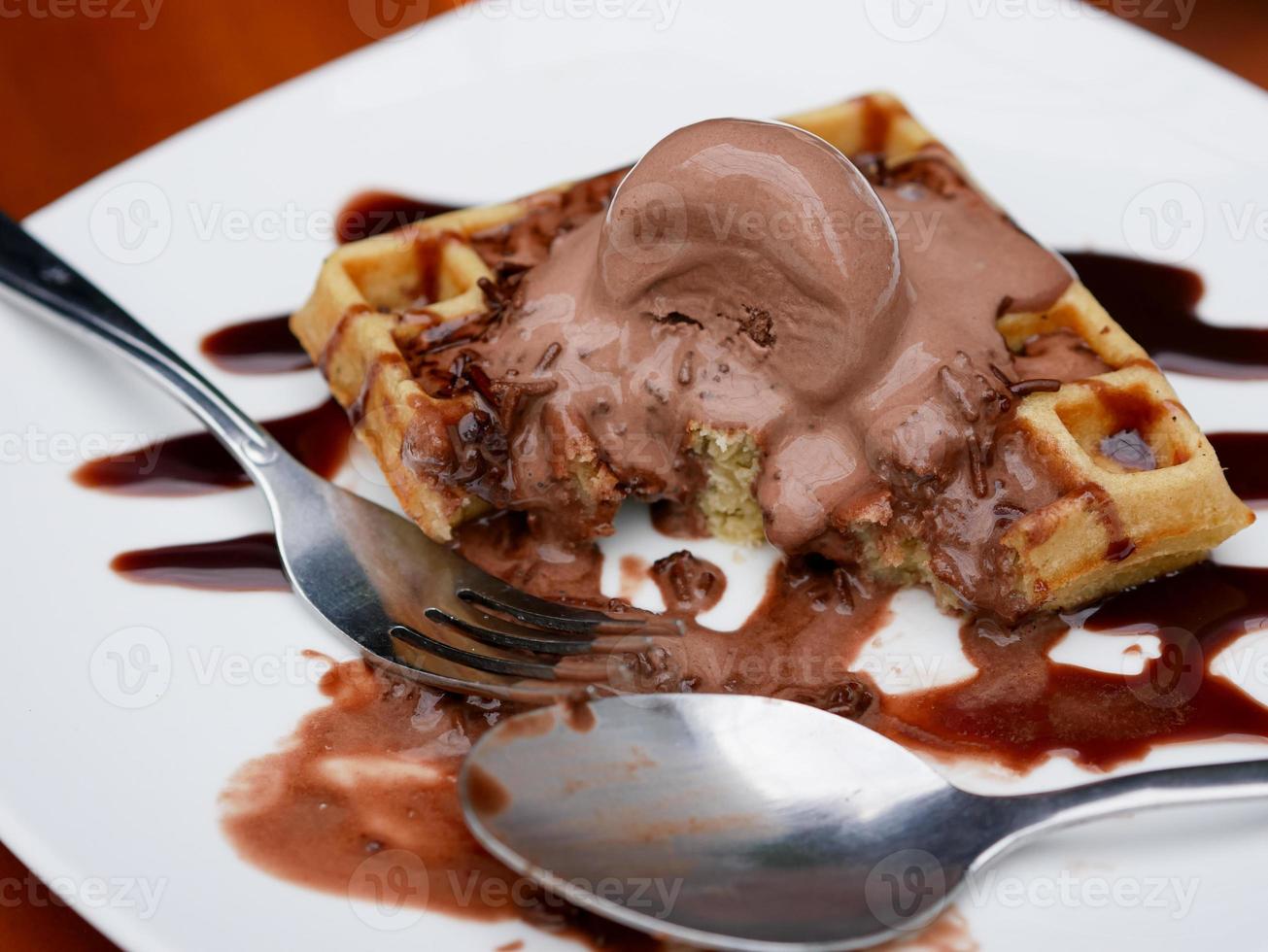 Chocolate waffle already sliced with ice cream topping on a plate photo