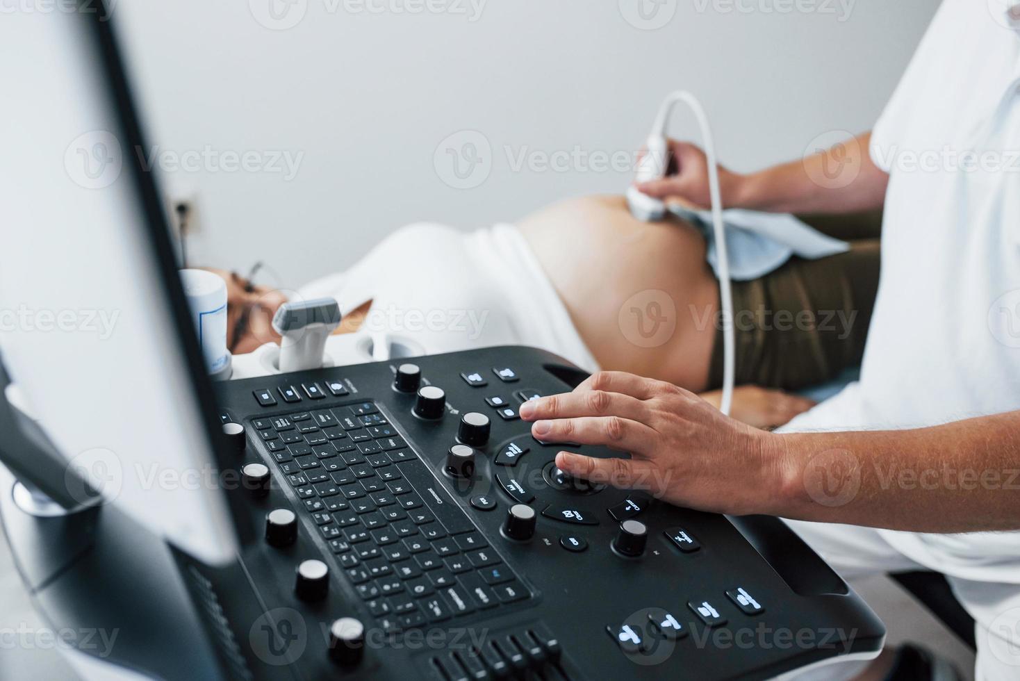 médico masculino hace ultrasonido para una mujer embarazada en el hospital foto
